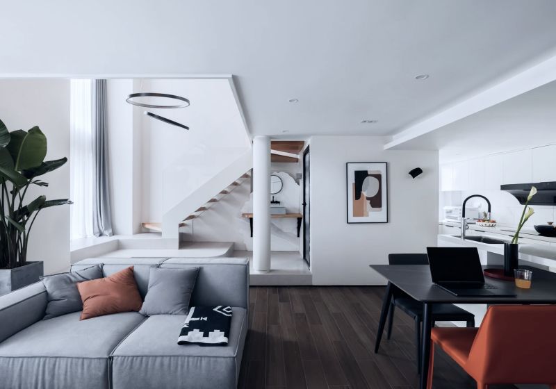Modernes helles Wohnzimmer mit einem dunklen Tisch und einer Treppe im Hintergrund